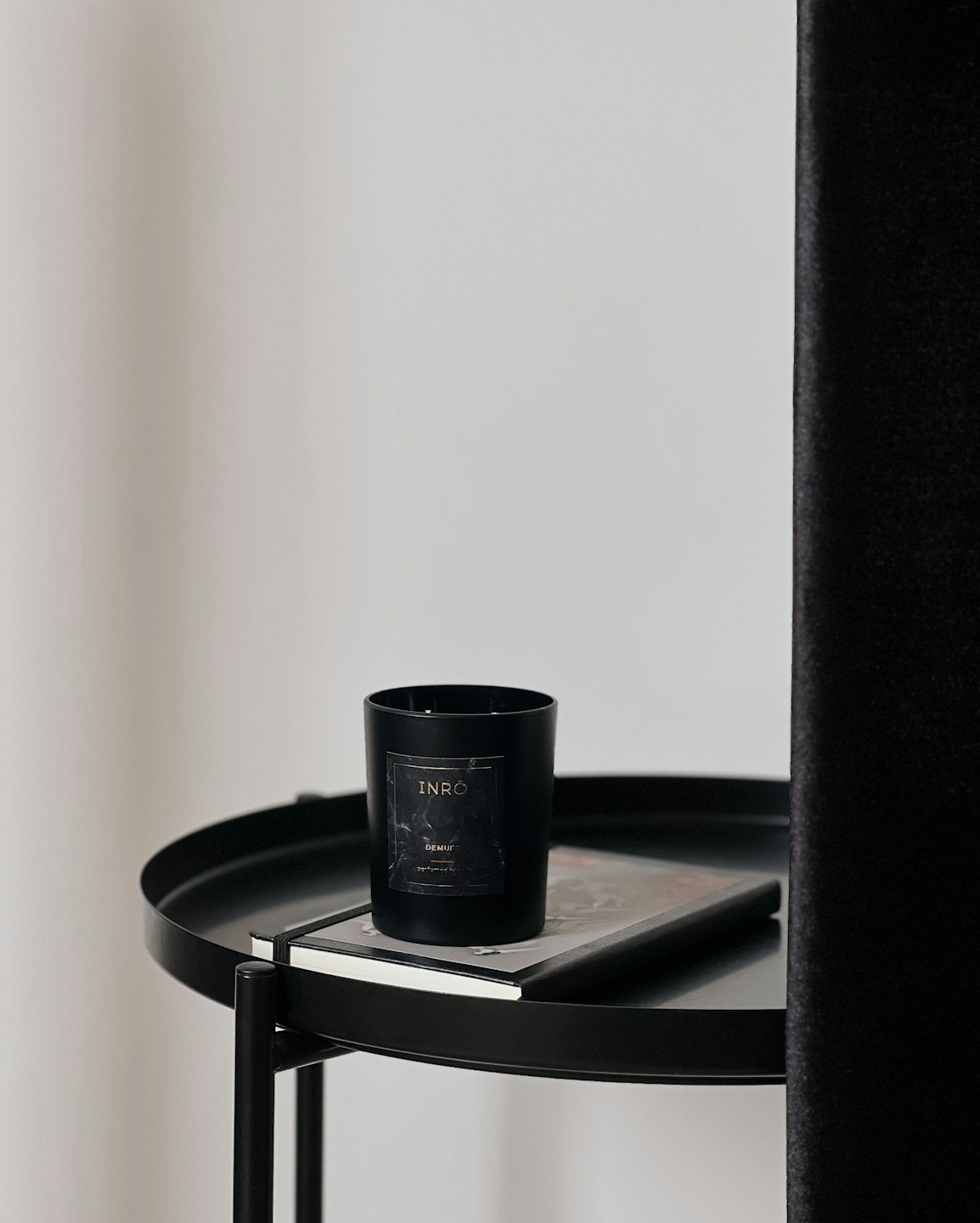 Scented candle and notebook sitting on a black side table.